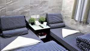 A hotel room with a marble wall, a small table with a telephone, two potted plants, and striped bedding. - Sydney Hostel (Kowloon)