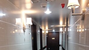A corridor with black and white tiled walls, a black marble floor, and wall-mounted light fixtures. - Sydney Hostel (Kowloon)