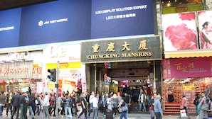 A busy street with a hotel entrance, signage, and pedestrians. - Sydney Hostel (Kowloon)