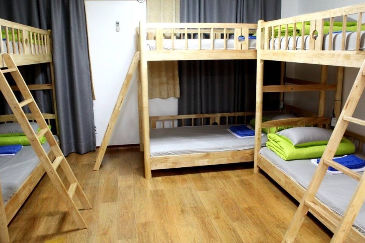 A room with three bunk beds, each with a ladder, and a small table in the center.