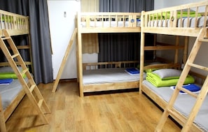 A room with three bunk beds, each with a ladder, and a small table in the center. - Welcome Busan Guesthouse (Busan)