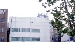 A modern building with large windows and a parking lot in front. - Welcome Busan Guesthouse (Busan)