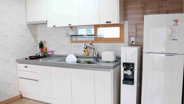 A compact kitchen with white cabinets, a built-in sink, a toaster, and a refrigerator. - Welcome Busan Guesthouse (Busan)