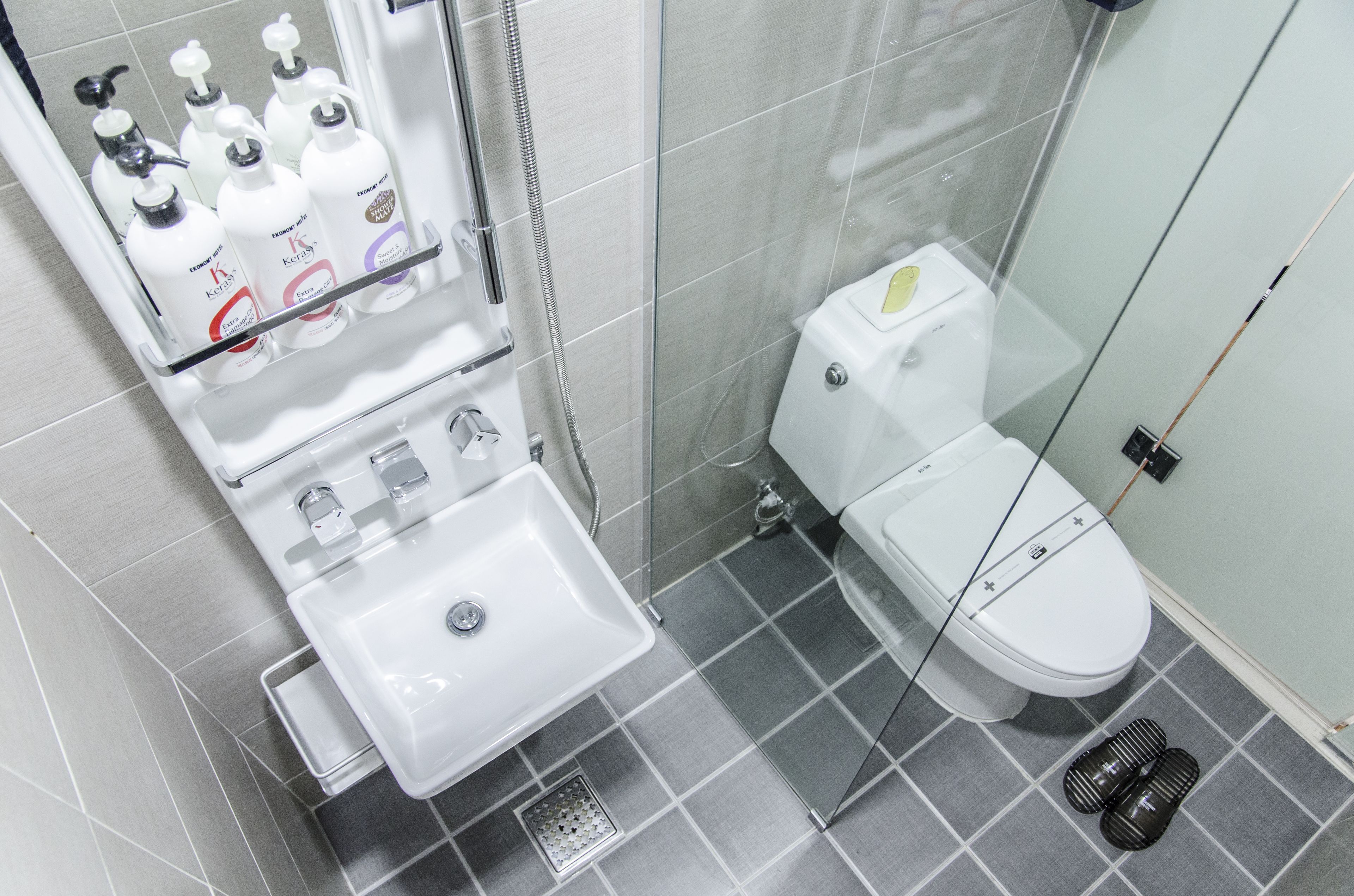 Une salle de bain moderne avec un lavabo, des toilettes et une douche, le tout de couleur blanche.