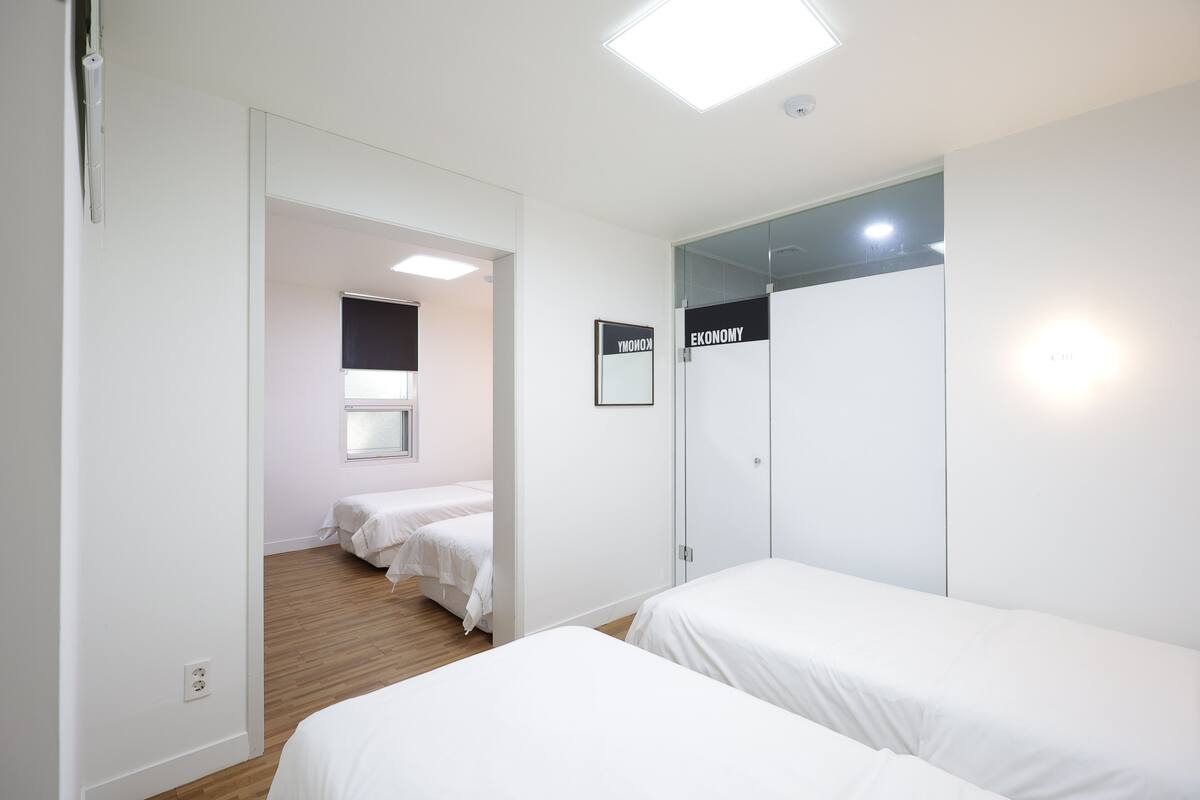 Habitación de hotel con dos camas individuales, un armario y un espejo.