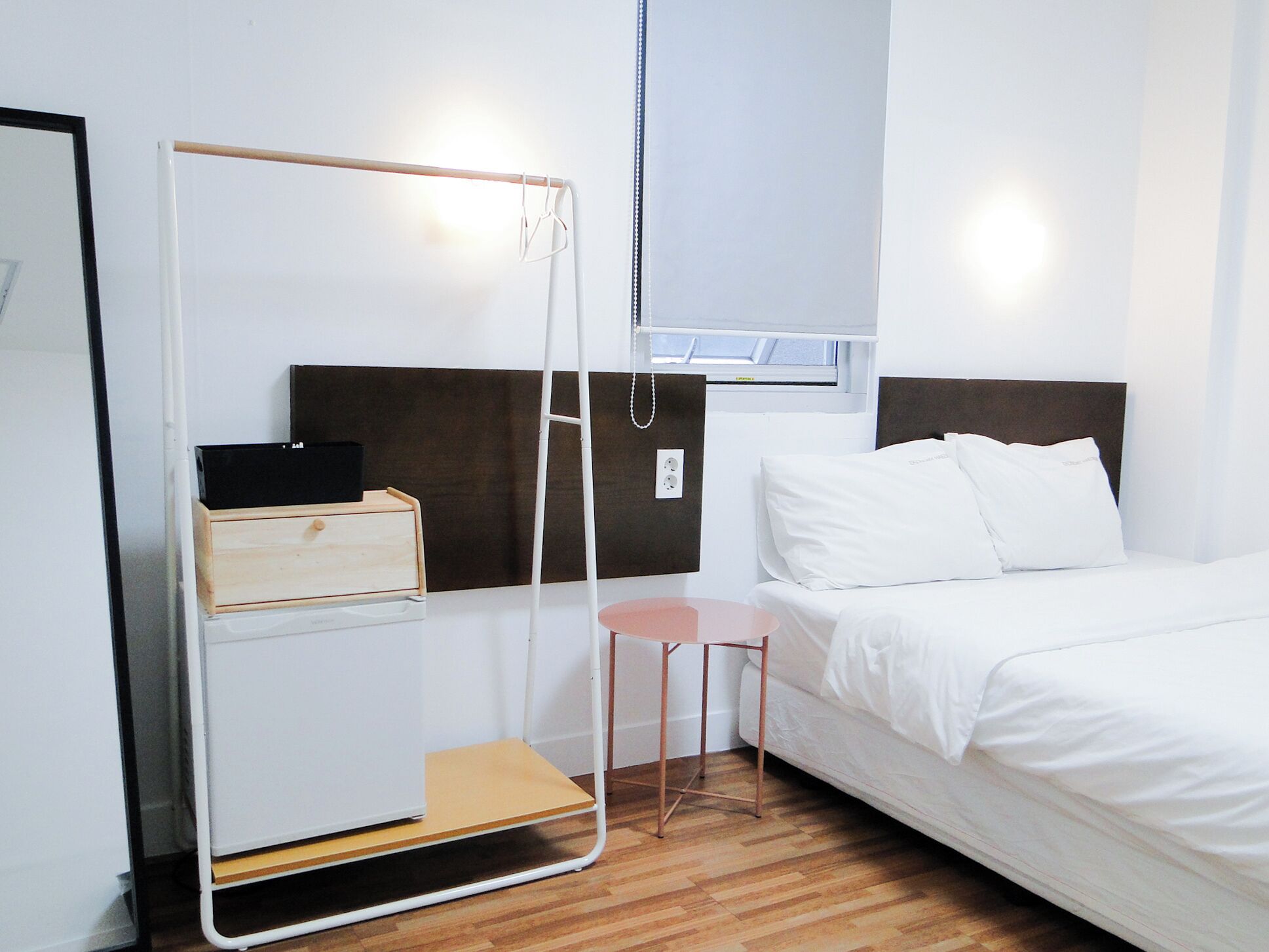 Una camera da letto con un letto, uno sgabello, un armadio bianco e una finestra.