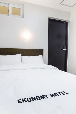 A bed with a white bedspread and a sign that reads "EKONOMY HOTEL" on it. - Ekonomy Haeundae Guesthouse (Busan)