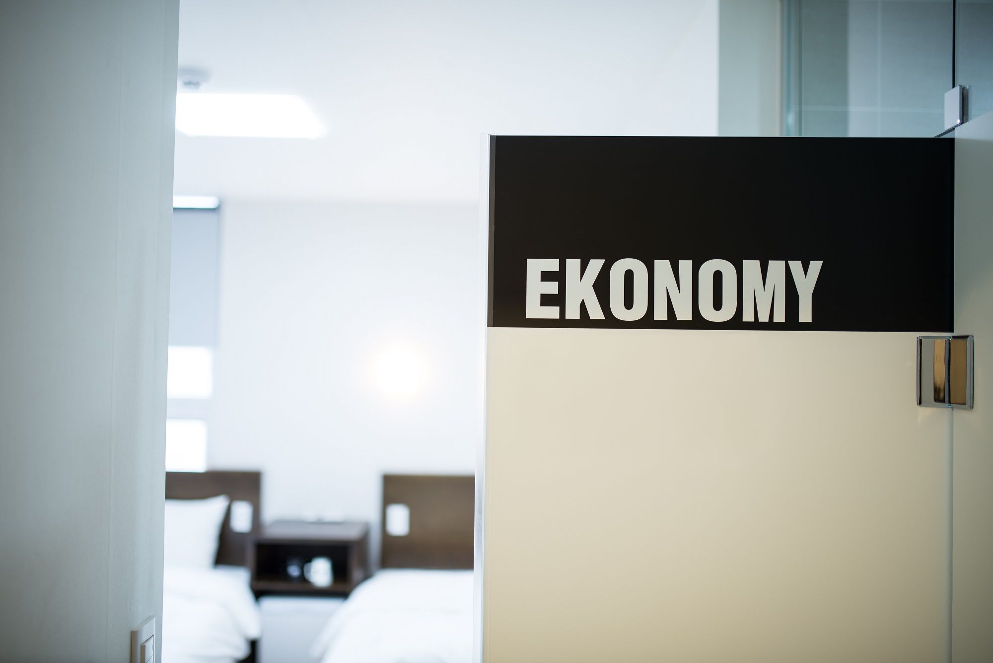 A hotel room with a sign labeled "EKONOMY" on the door, indicating a budget-friendly option.