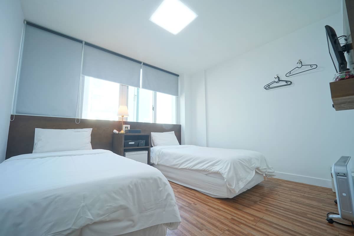 Una habitación de hotel con dos camas, un escritorio, una lámpara y un televisor.
