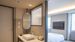 A modern hotel room with a large bed, a built-in TV, a large mirror, and a bathroom with a sink and towel rack. - Wishton Hotel Yukari (Sakura)