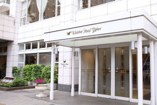 The exterior of the Wishton Hotel Yukari with a modern facade, large glass doors, and a signboard.