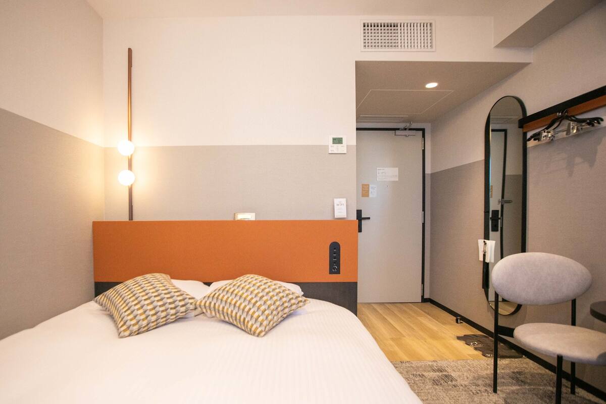 A hotel room with a bed, a chair, and a mirror.