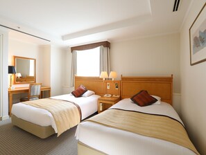 A hotel room with two beds, a desk, a chair, a mirror, and a window with curtains. - Wishton Hotel Yukari (Sakura)