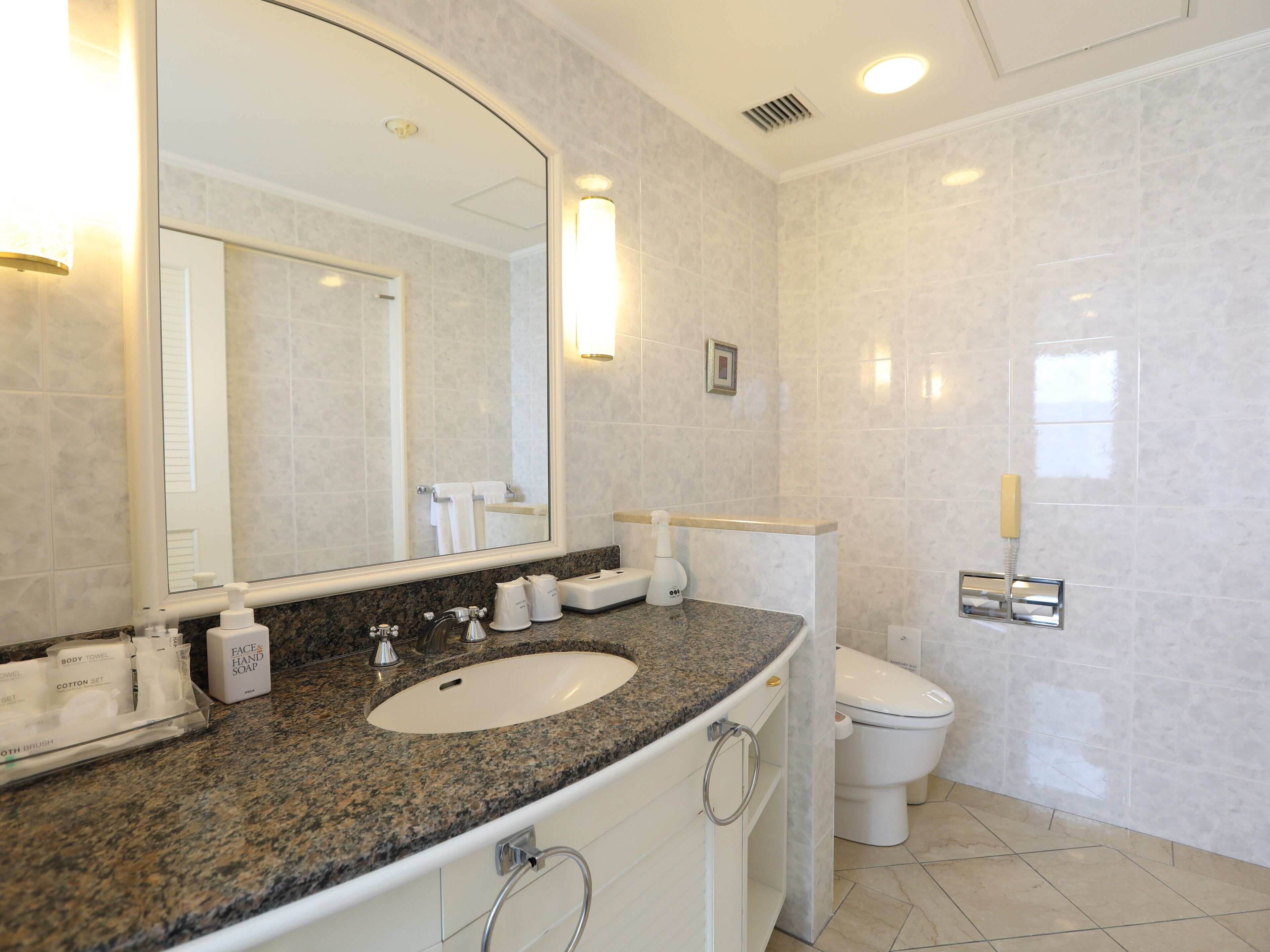 A modern bathroom with a granite countertop, a white sink, and a toilet.
