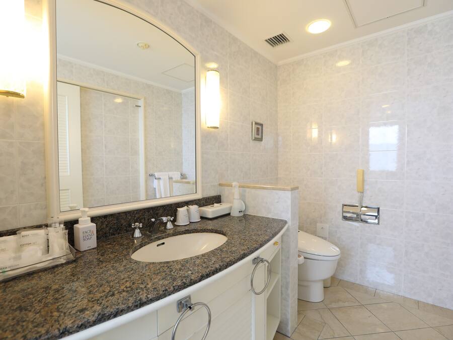 A modern bathroom with a granite countertop, a white sink, and a toilet.