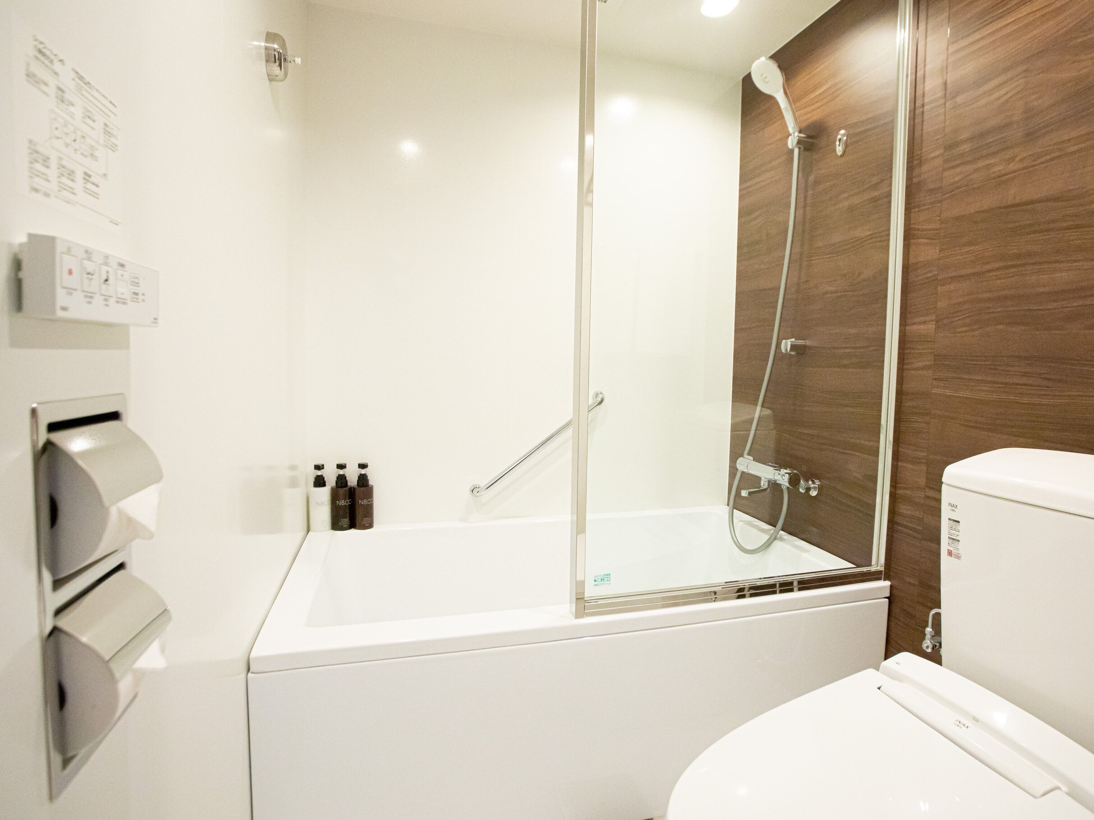 A modern bathroom with a glass-enclosed shower, a white bathtub, and a toilet.