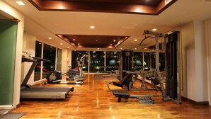 Une salle de sport équipée de tapis de course, d’appareils de musculation et de ballons d’exercice.