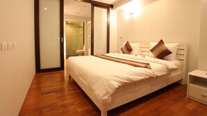 Une chambre moderne avec un grand lit, un plancher en bois et une porte-fenêtre coulissante donnant sur une salle de bain.