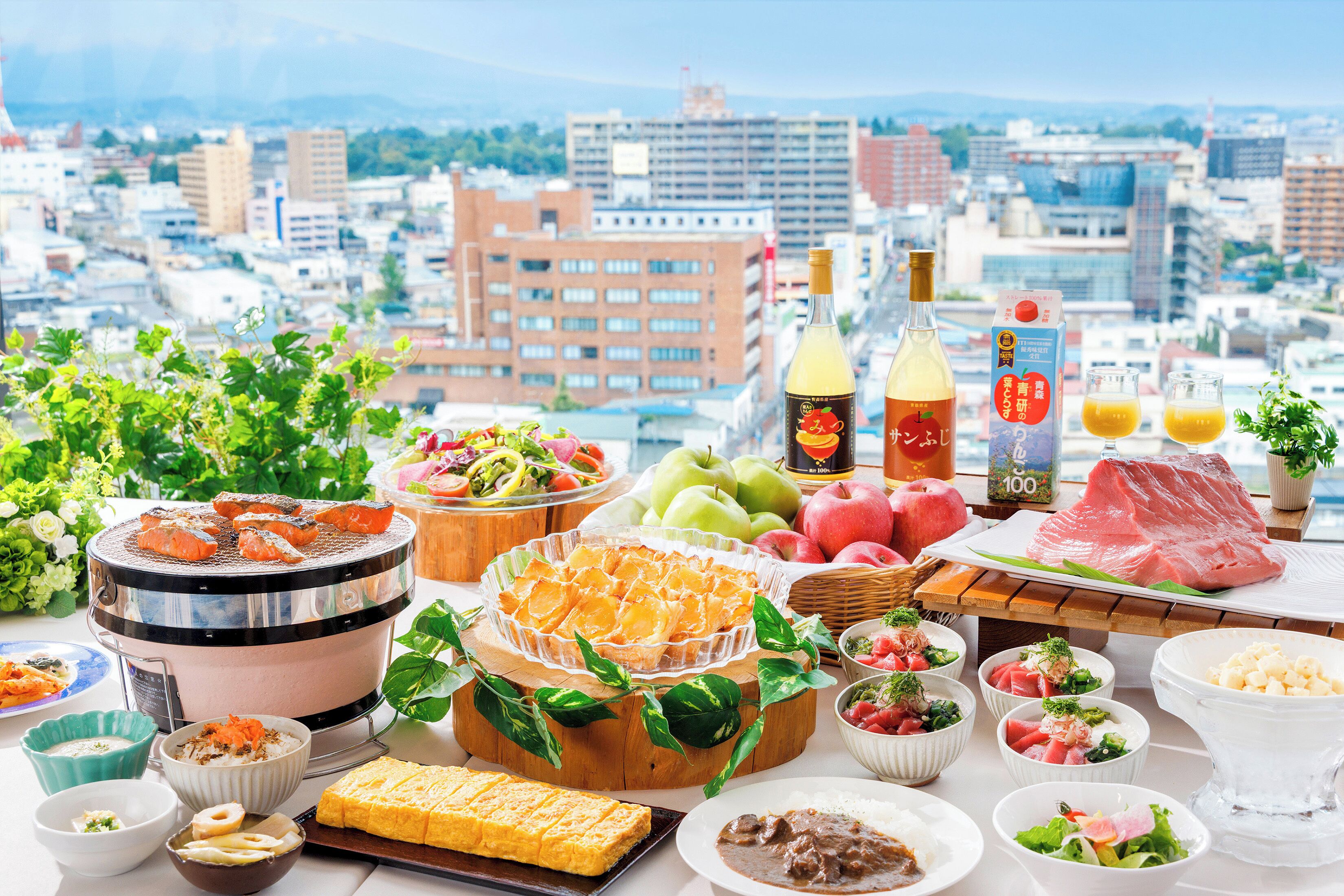 A table set with various Japanese dishes, including sashimi, rice, and vegetables, with a cityscape view in the background.