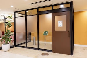 A hotel entrance with a sliding glass door, a potted plant, and a designated smoking area sign. - Hirosaki Park Hotel (Hirosaki)