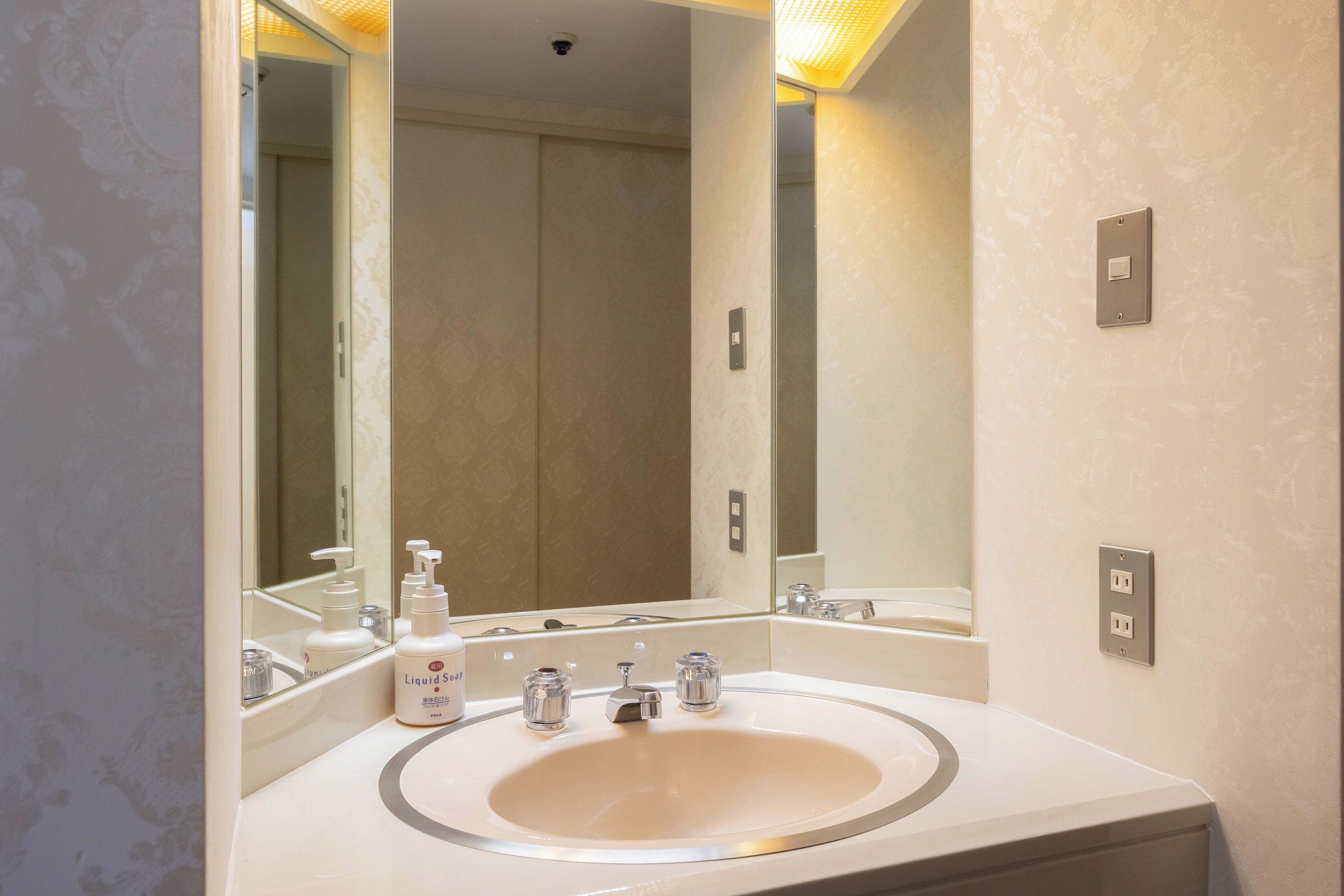 A bathroom with a large mirror, a sink, and a toilet.