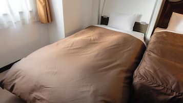 A single bed with a brown bedspread and matching pillow in a hotel room.