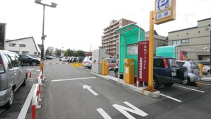 Un estacionamiento con coches, un edificio verde y un cartel con caracteres japoneses.