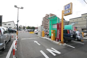 Un estacionamiento con coches, un edificio verde y un cartel con caracteres japoneses.