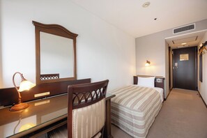 Habitación de hotel con cama, mesita de noche, lámpara, espejo y una puerta que da a otra habitación.