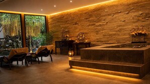 A modern interior with a stone wall, a wooden reception desk, and a seating area with chairs. - The Orchard Resort & Spa Melaka (Alor Gajah)
