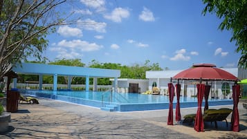 Een buitenzwembad, parasols bij het zwembad en ligstoelen