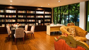 A library with bookshelves, a wooden floor, a desk, and a sofa.
