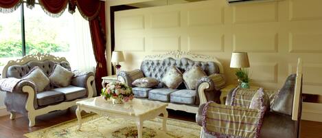 A spacious living room with a large sofa set, a coffee table, and a decorative rug.