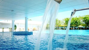 A swimming pool with water jets, a tiled ceiling, and a poolside area with umbrellas. - The Orchard Resort & Spa Melaka (Alor Gajah)
