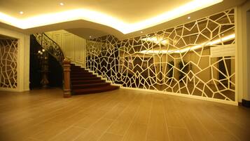 A spacious lobby with a wooden staircase and a geometric wall design.