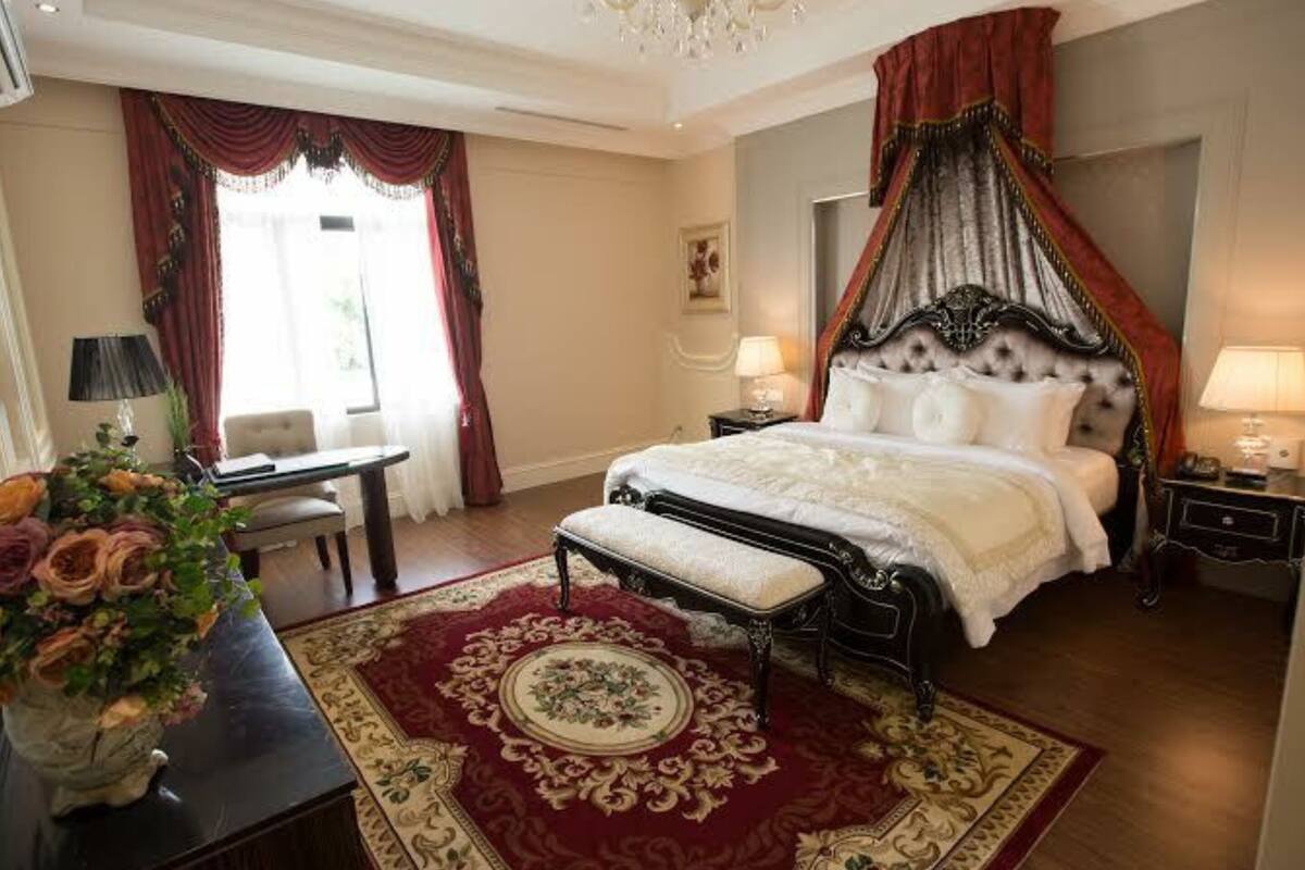 Ein geräumiges Schlafzimmer mit einem großen Bett, einer Sitzecke mit Tisch und Stühlen sowie einer dekorativen Vase mit Blumen.
