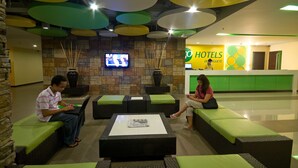 A hotel lobby with wicker furniture, a stone wall, and a TV.