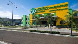 A hotel with a prominent sign, a modern design, and a landscaped area with palm trees.