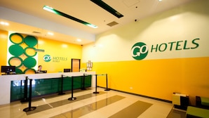 A reception area with a check-in counter, a reception desk, and a wall with the logo "GO HOTELS". - Go Hotels Iloilo (Iloilo)