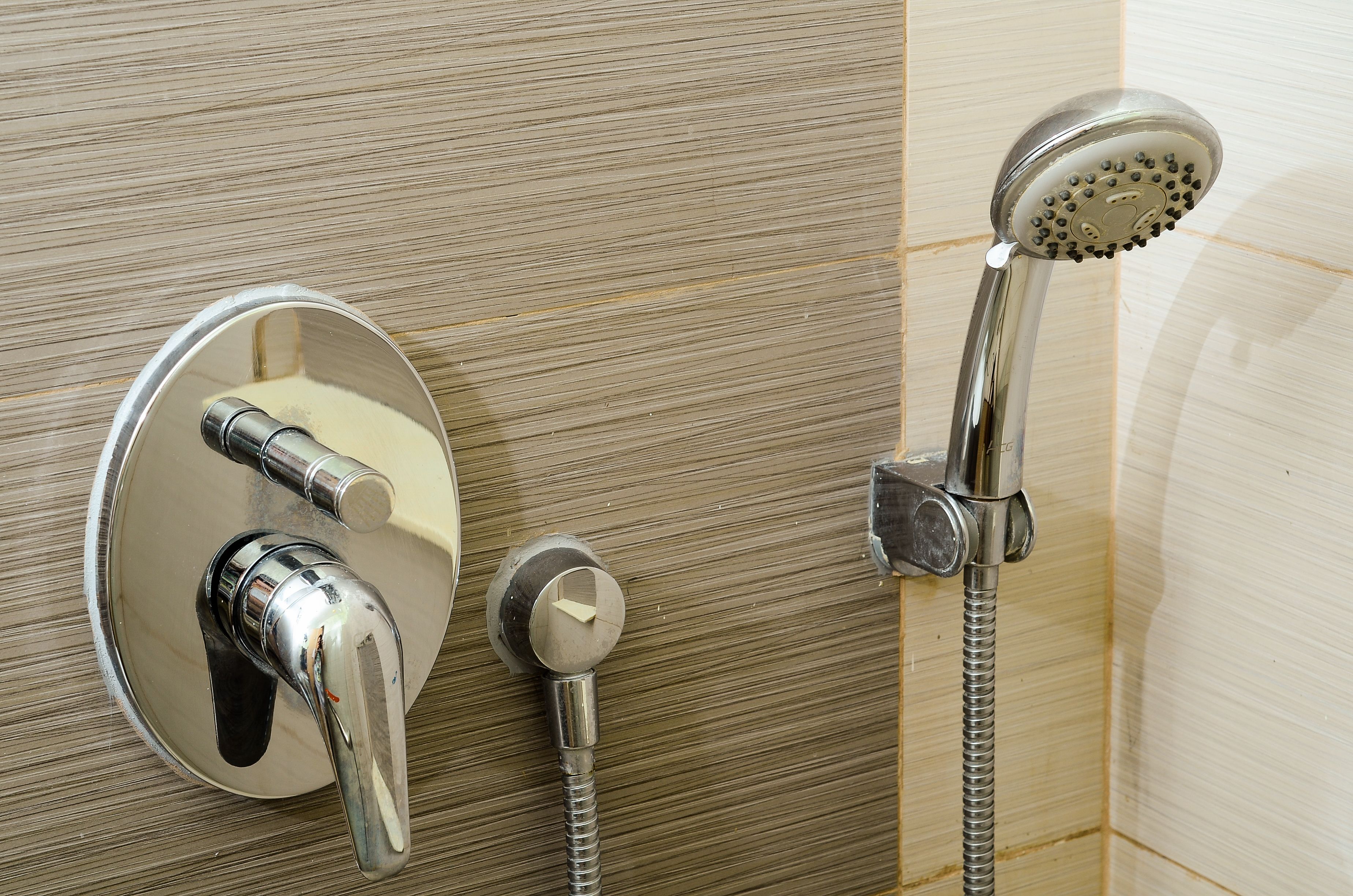 Een badkamer met een in de muur gemonteerde douche, een handdouche en een apart kranenwerk.