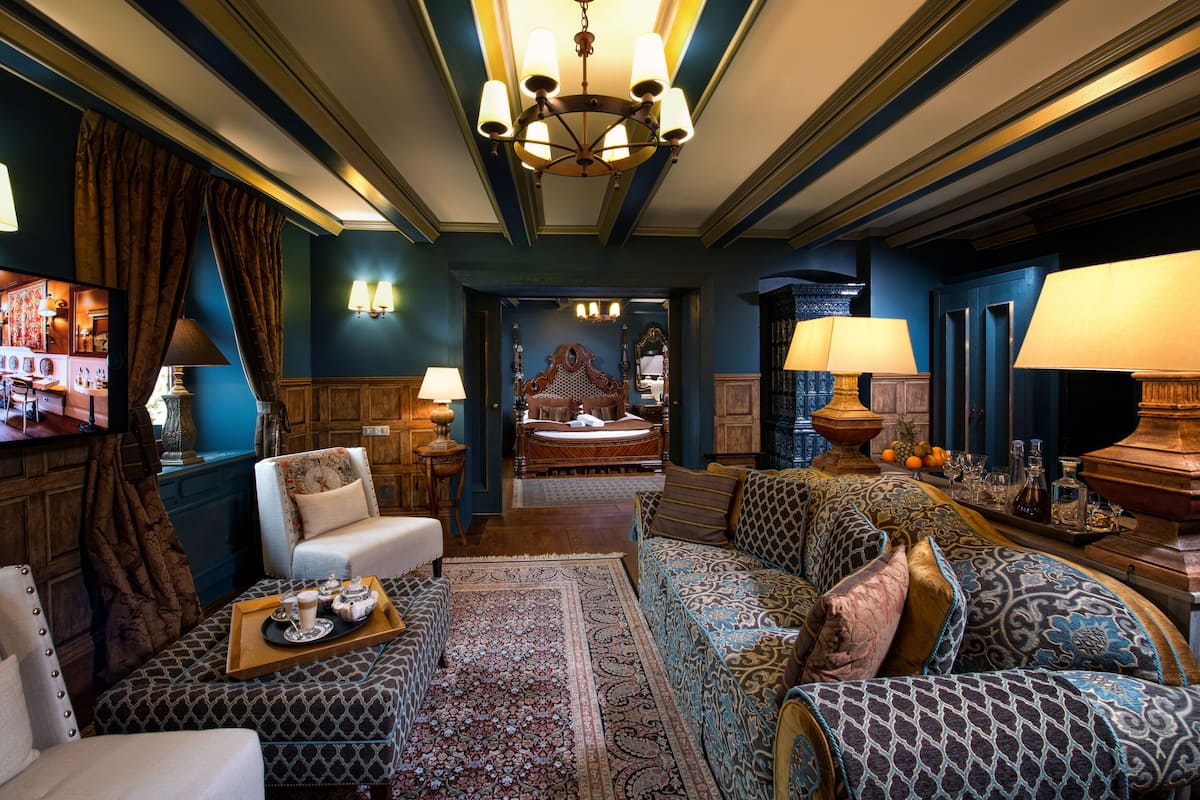 Um hall de hotel luxuoso com um sofá grande, uma mesa de centro de madeira e um tapete estampado.