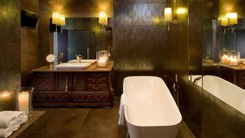 A luxurious bathroom with a freestanding bathtub, a double vanity with a mirror, and wall sconces.