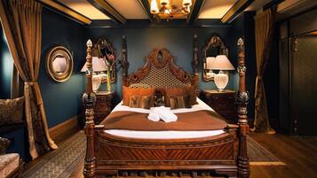 A large, ornate bed with a wooden headboard, flanked by two nightstands with lamps, in a room with dark walls and a patterned rug.