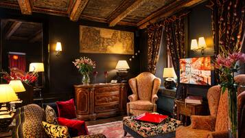 A traditional room with ornate ceiling, a large painting, and classic furniture.