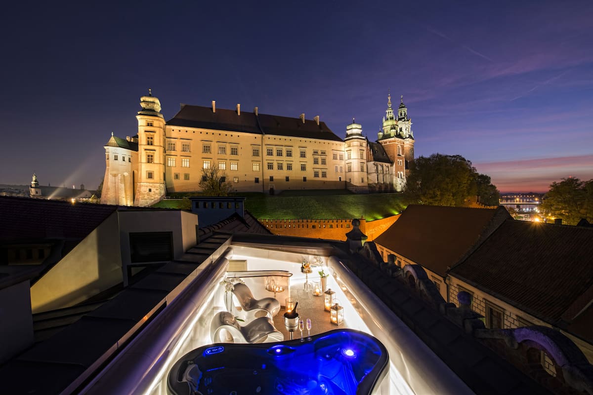 Terraço com banheira de hidromassagem e vista para um edifício histórico com várias torres.
