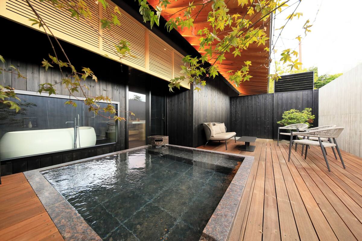 Ein moderner Wellnessbereich mit Holzterrasse, Whirlpool und Sitzgelegenheiten.