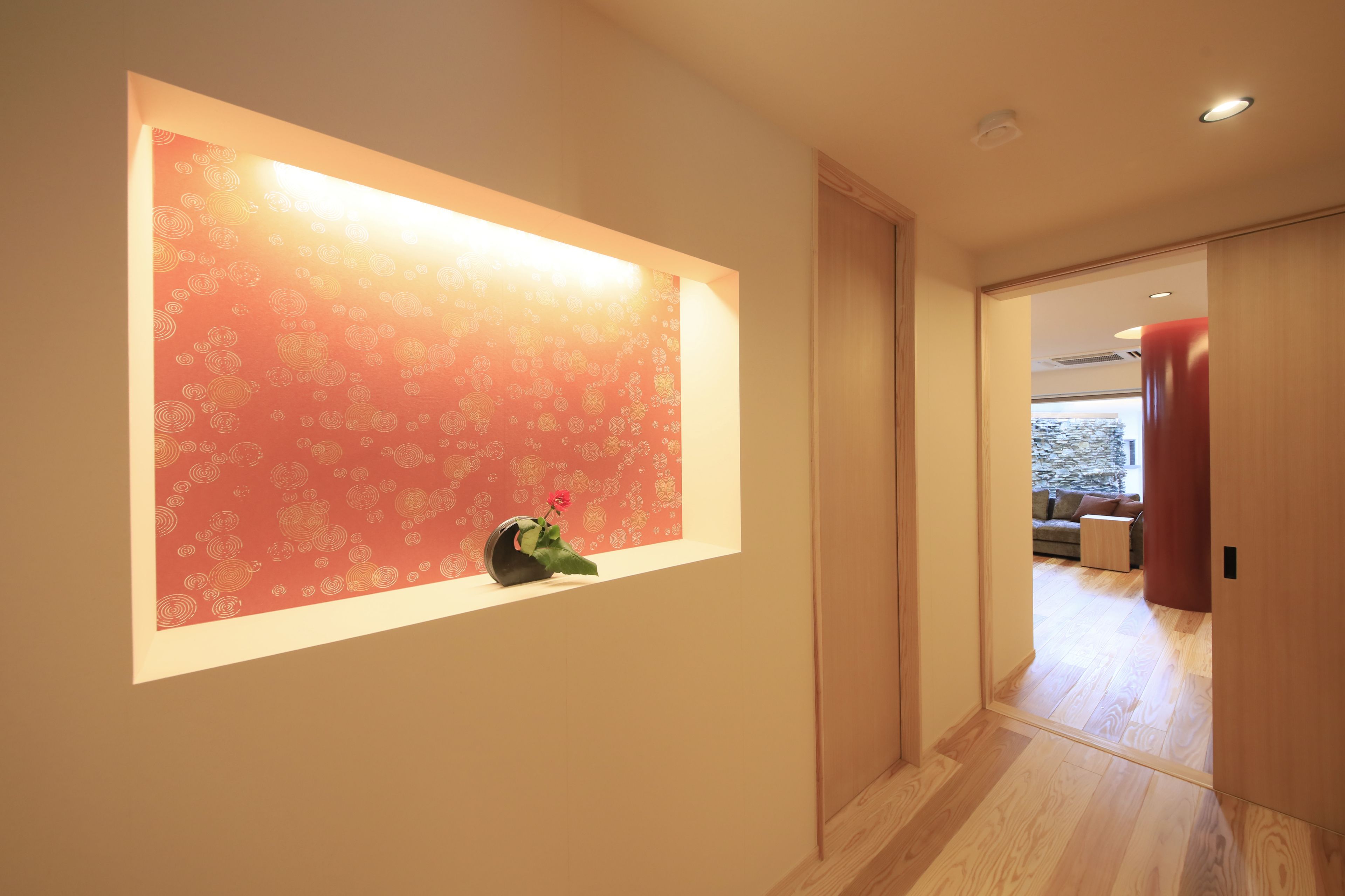 A hallway with a window displaying a patterned wall and a small plant.