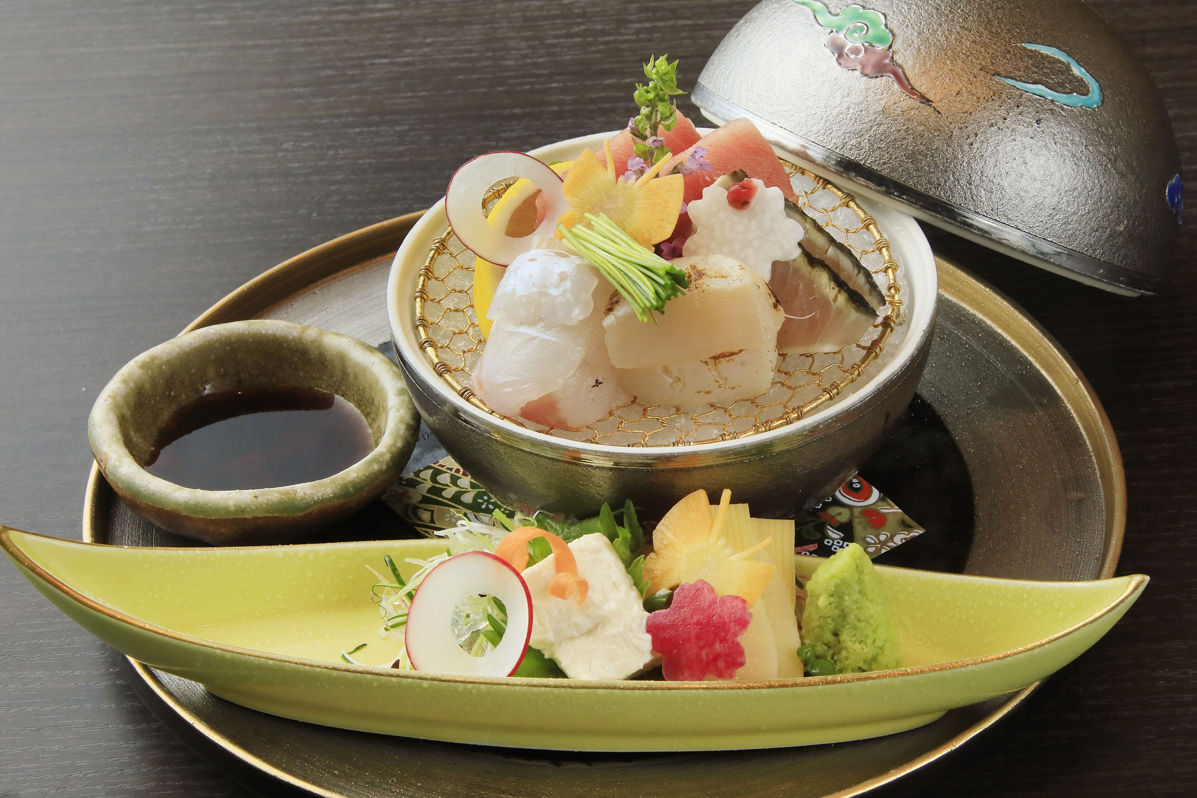 A traditional Japanese meal with sashimi, a small bowl of soy sauce, and a decorative ceramic dish.