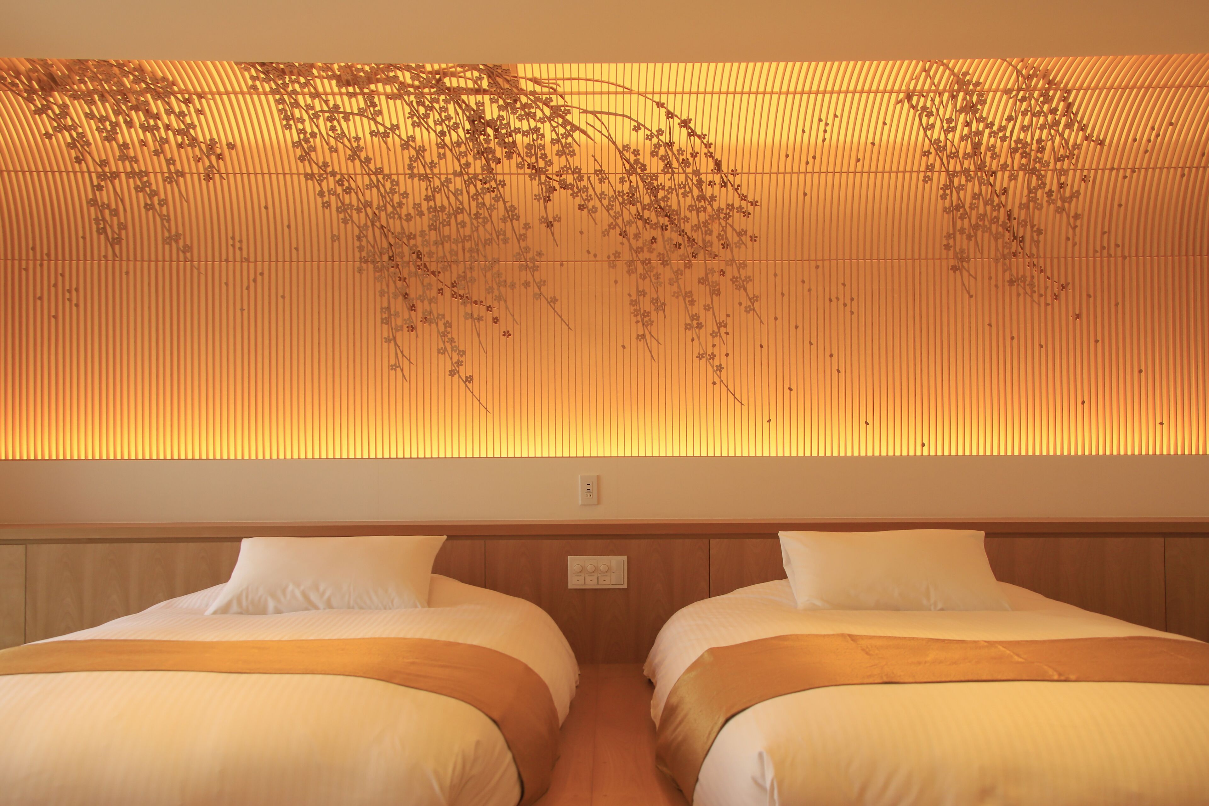 A hotel room with two beds, a wooden headboard, and a wall with vertical lines and hanging plants.