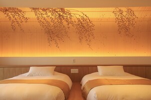 A hotel room with two beds, a wooden headboard, and a wall with vertical lines and hanging plants.